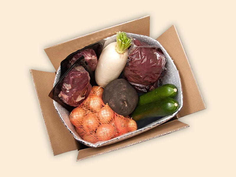 Frisches vakuumiertes Fleisch und frisches Gemüse ist in einer Isolierverpackung in einen Versandkarton gepackt
